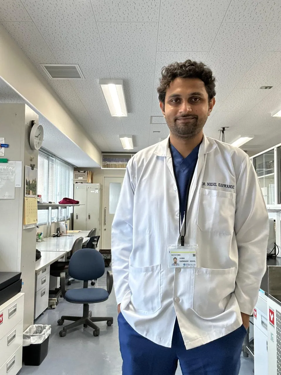 Dr. Karwande in a Shiga University lab coat with his name badge
